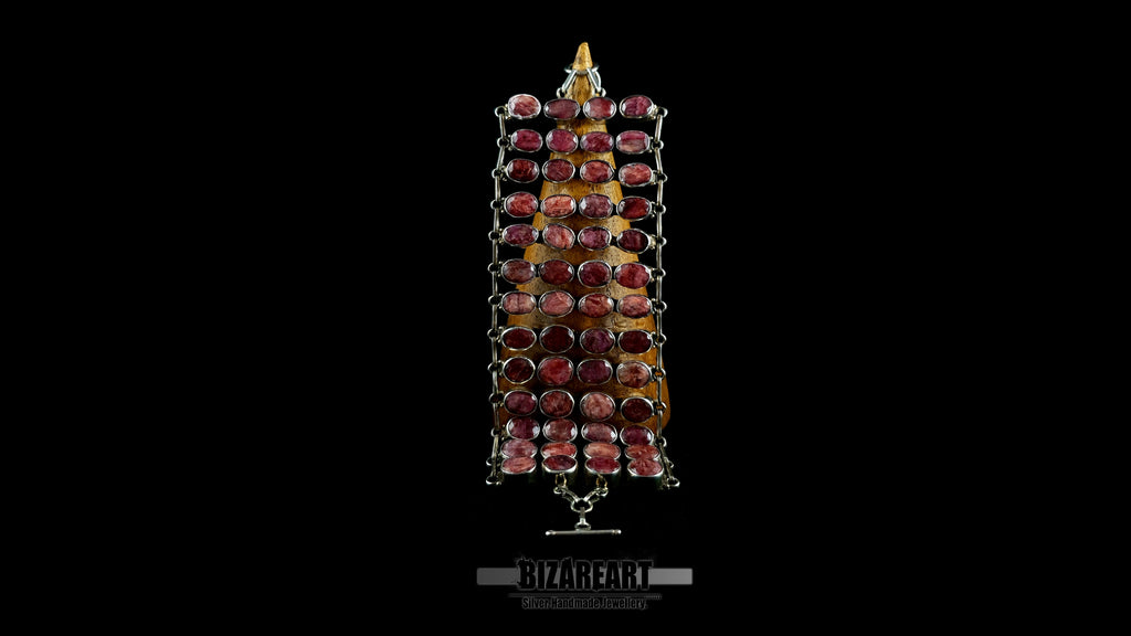 Imperium wide sterling silver armor collar with 52 hand-set raw ruby stones displayed vertically on a wooden cone against a black background.