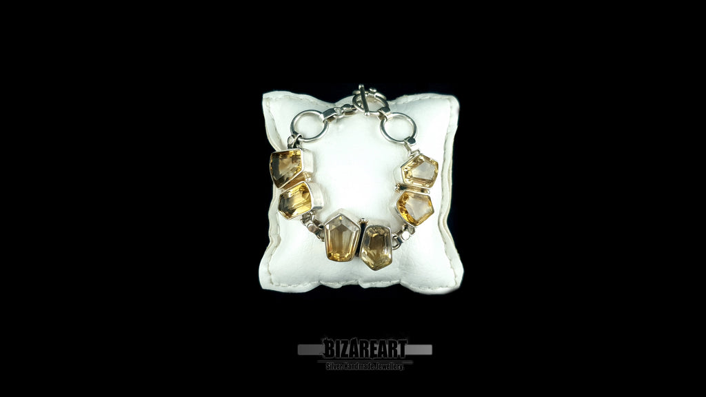 Handmade Greek silver citrine bracelet draped over a luxury white leather pillow