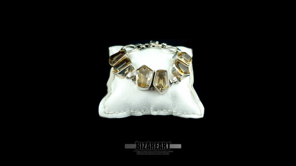 Angled front view of geometric citrine gemstones set in heavy sterling silver on white cushion