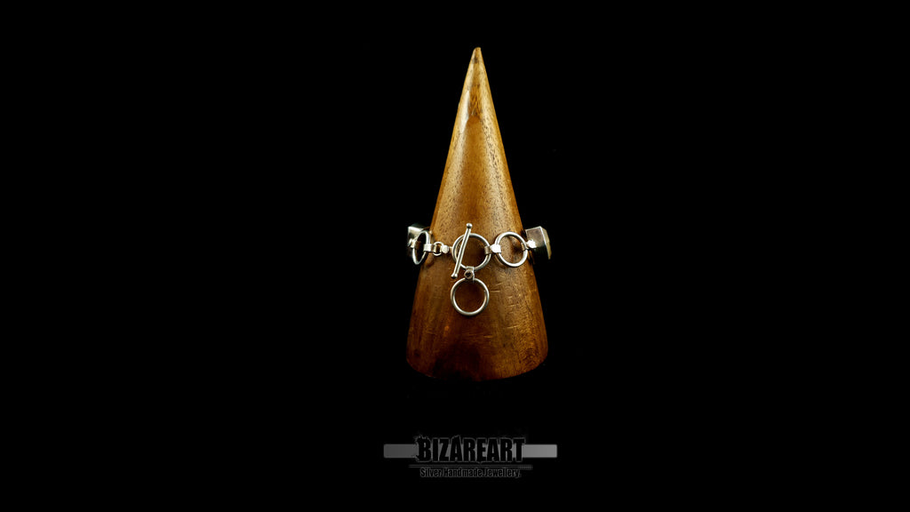 Back side perspective of architectural silver links and raw-cut citrine gemstones on wooden cone