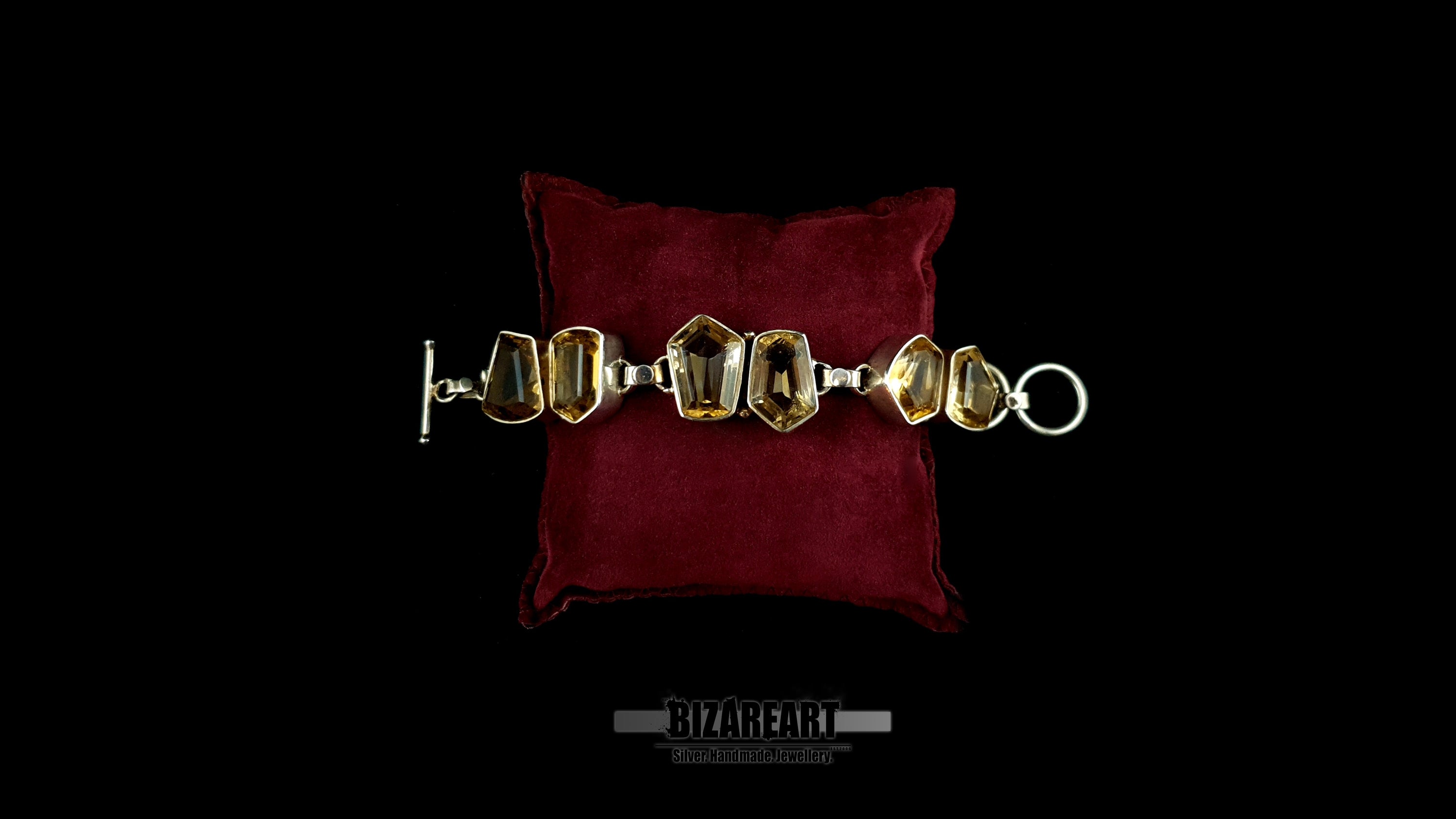 Full-length view of raw citrine silver bracelet laid open with toggle bar closure on red velvet