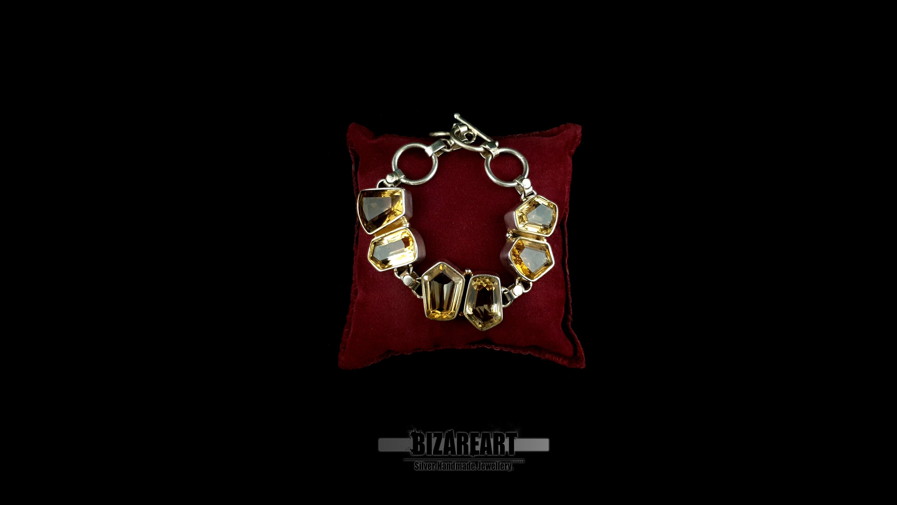 Handmade sterling silver bracelet with six raw geometric citrine gemstones displayed on red velvet pillow
