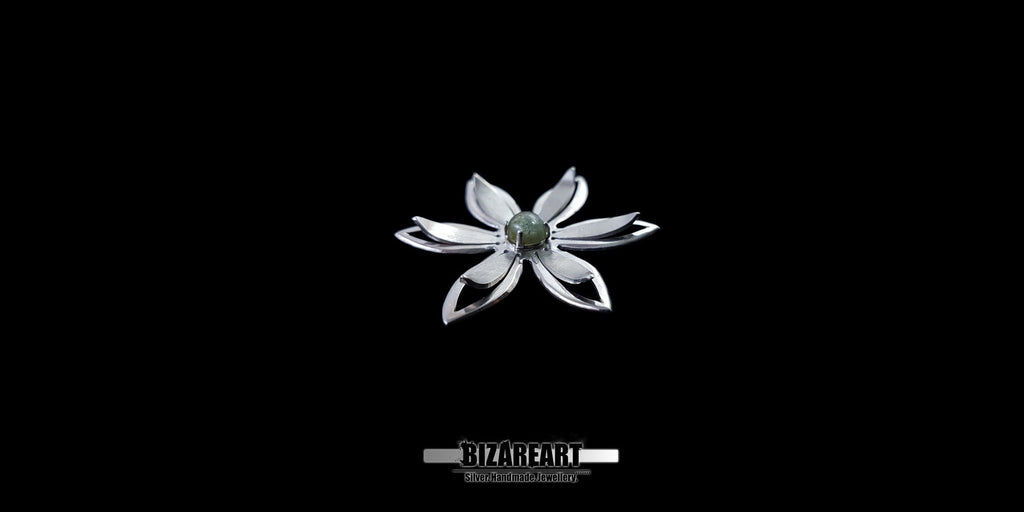 A series of product photography shots showing the silver flower pendant from various angles on a black background, highlighting the metallic sheen and the depth of the central gemstone.