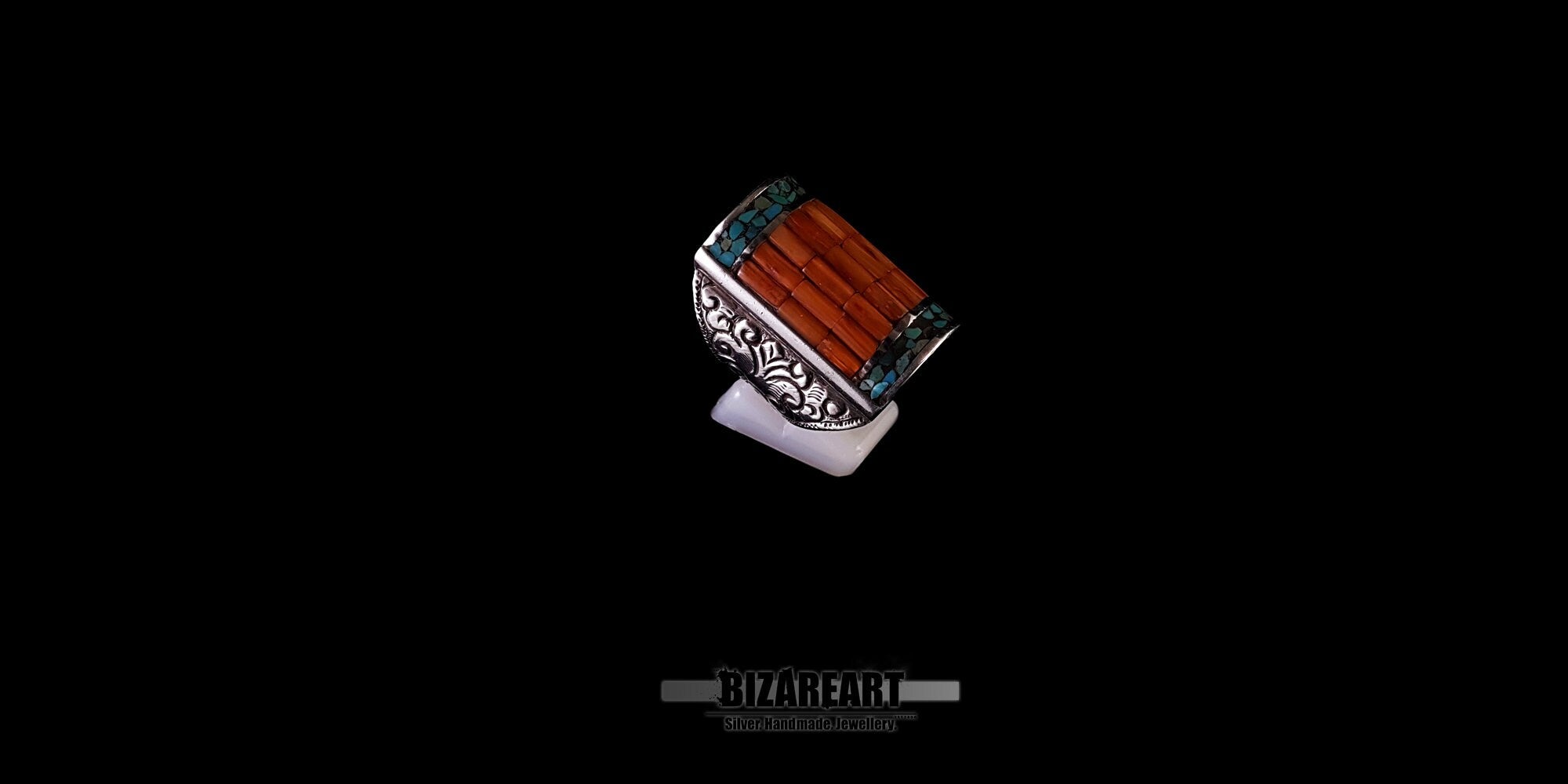 Top-down close-up of a vintage handmade Tibetan ring showcasing the bold combination of rectangular red coral slices and a fine turquoise border.