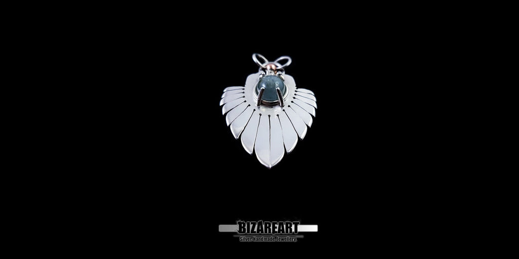 Front view of the Silver Wings Pendant featuring a central Blue Tourmaline stone in a claw setting, showcasing the radial carved silver lines against a black background.