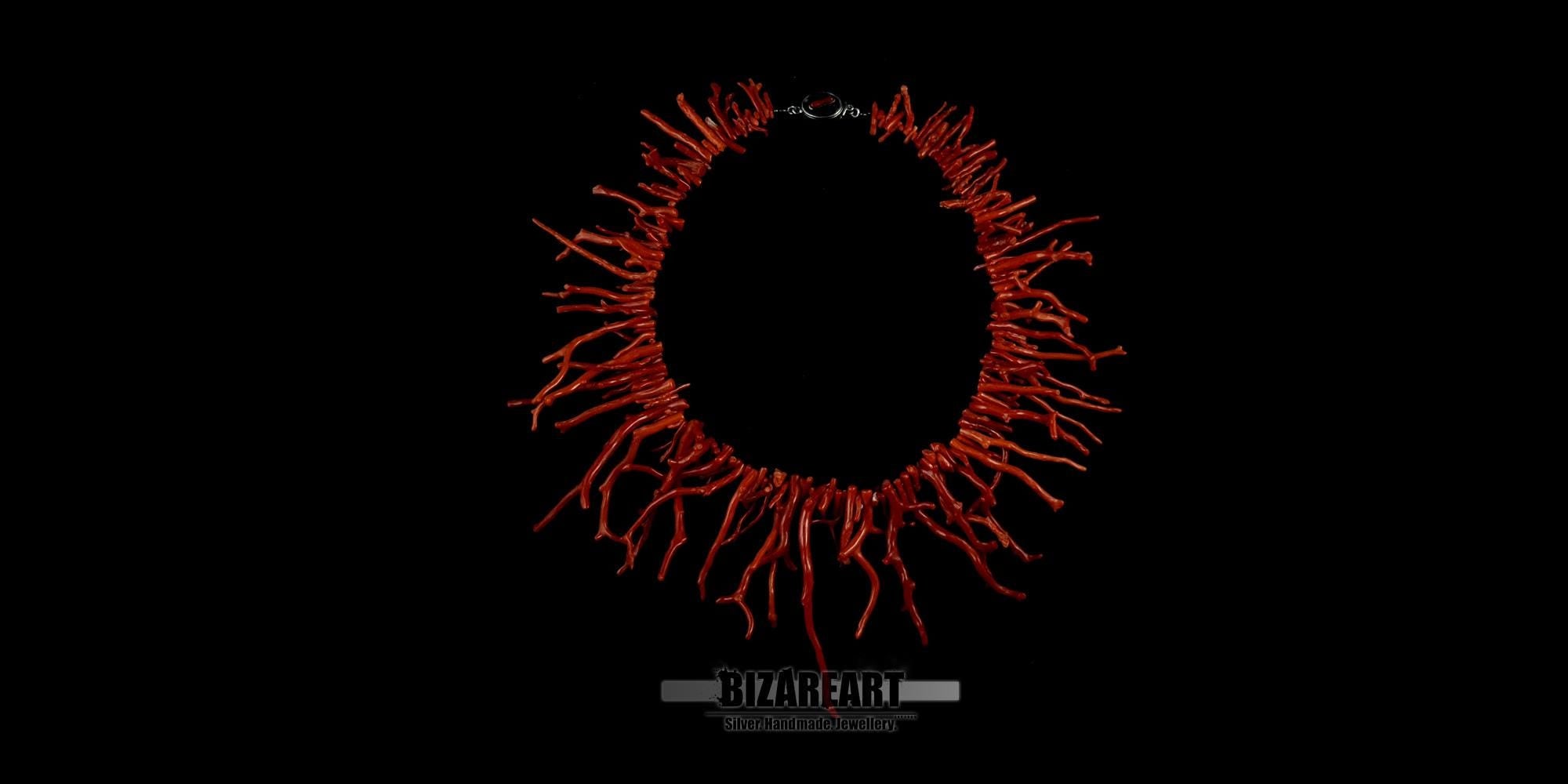 Flat lay of a handmade Mediterranean red coral branch statement necklace by Bizareart, isolated on a black background.