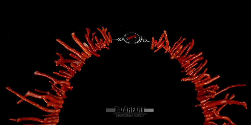 A focused view of the upper portion of the necklace, highlighting the transition from the silver closure to the vibrant red coral stems.
