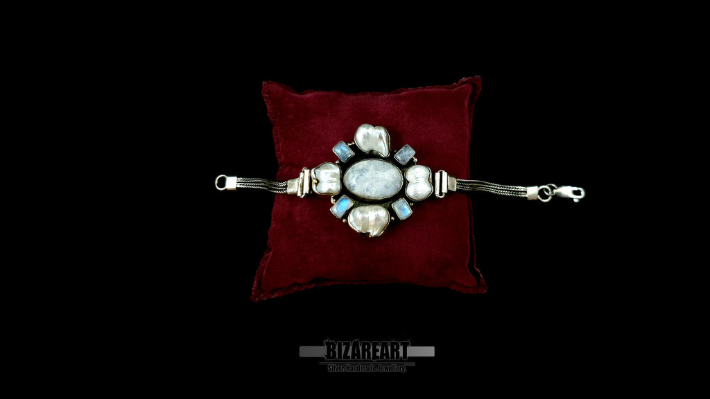 Handcrafted 35g sterling silver statement bracelet with 4 baroque pearls and 4 labradorite stones resting flat on a luxurious dark red velvet cushion.