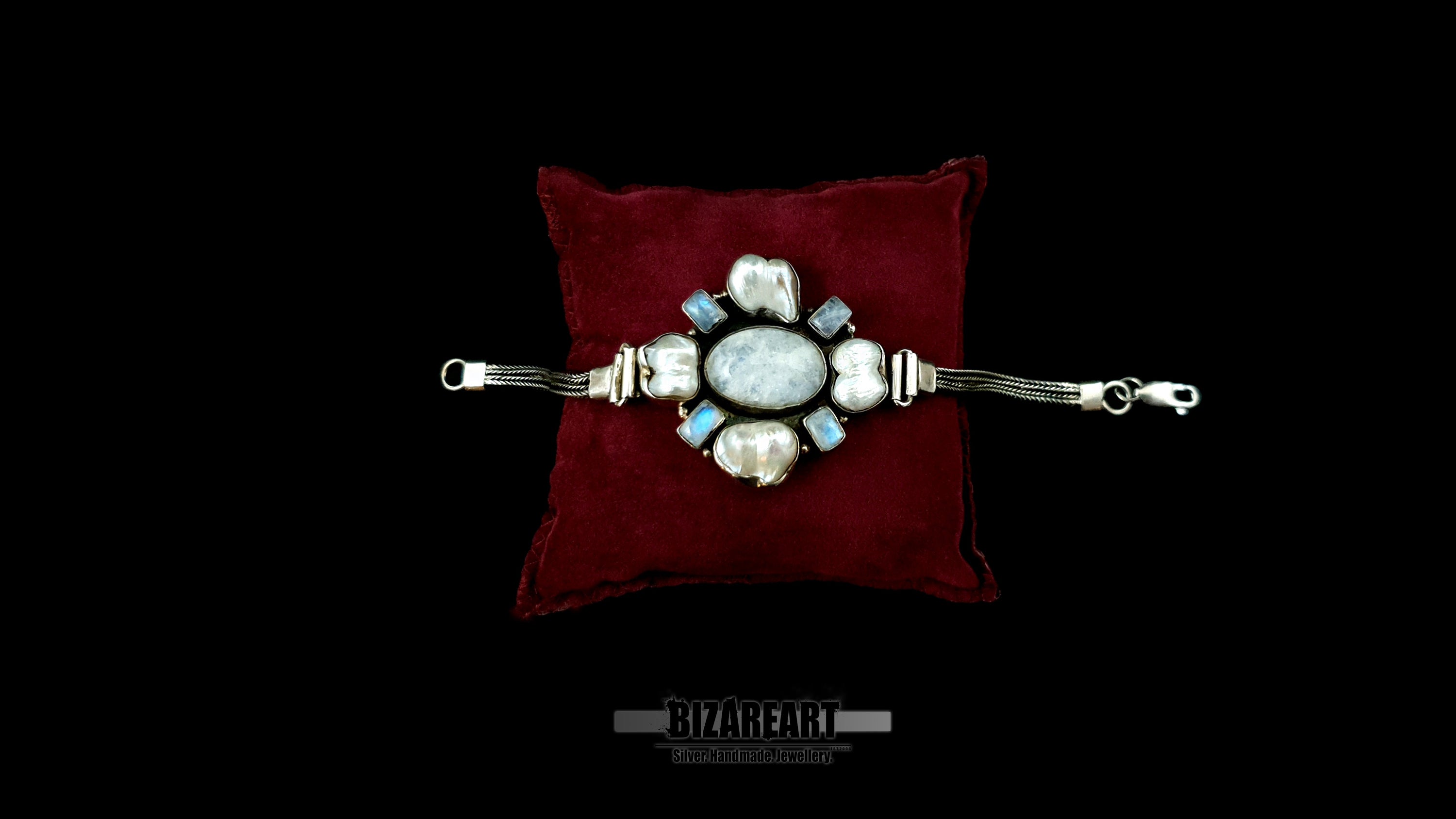 Handcrafted 35g sterling silver statement bracelet with 4 baroque pearls and 4 labradorite stones resting flat on a luxurious dark red velvet cushion.