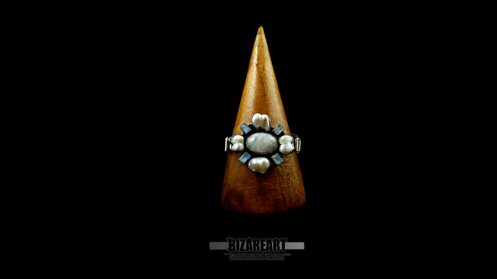 Symmetrical silver statement bracelet wrapped securely around a vertical wooden cone display to show its architectural profile and wrapping fit.