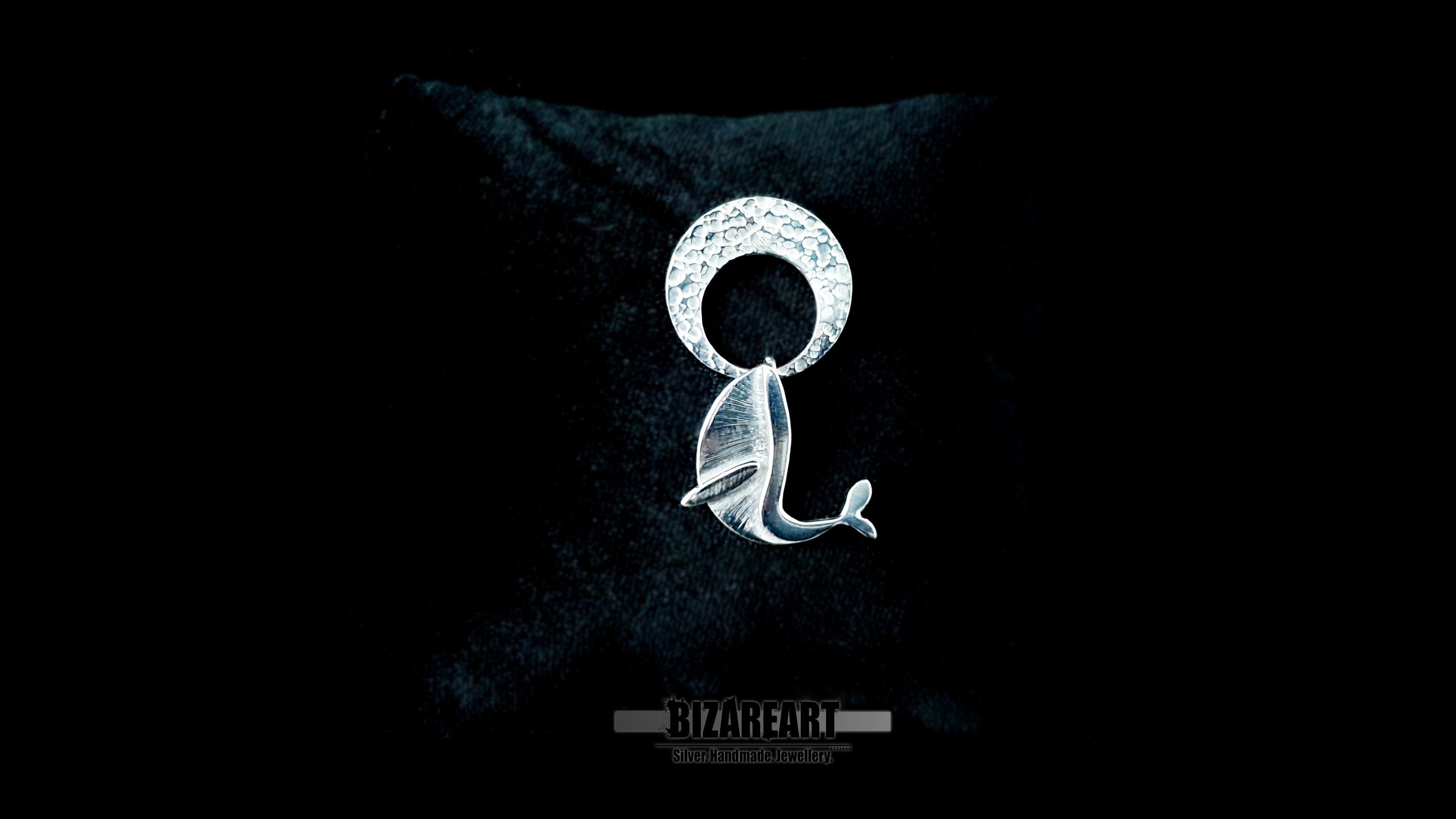 Video demonstration of the handmade kinetic silver pendant, showcasing the free-swinging movement of the whale breaching beneath the hammered crescent moon to highlight the interactive, multi-part design.